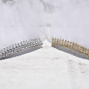 May include: Two rows of rhinestones, one silver and one gold, on a white tulle background.