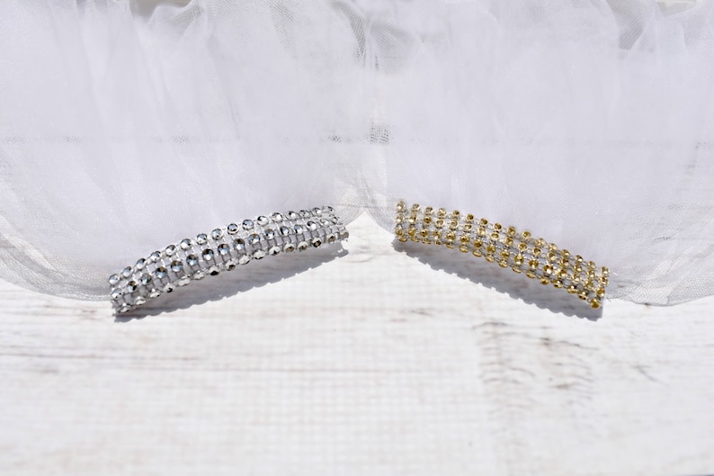 May include: Two rows of rhinestones, one silver and one gold, on a white tulle background.