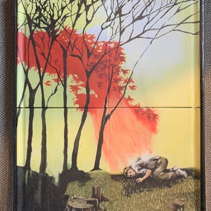 May include: Artwork featuring a surreal landscape with a person on the ground. The scene includes trees with red and black branches, a yellow and orange sky, and tree stumps. The artwork is framed in black.