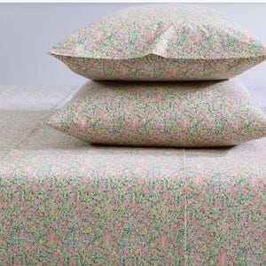 May include: A bed set featuring a floral pattern in pink, green, and yellow. Two pillows are stacked on top of a matching sheet. The bedding has a delicate, all-over floral design, creating a soft and inviting aesthetic. The sheets and pillowcases are made of a lightweight fabric.