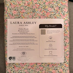 May include: A Twin Sheet Set by Laura Ashley, featuring a floral pattern in pink, yellow, and green. The packaging includes details about the cotton percale fabric, with dimensions for pillowcases and sheets, including a flat sheet measuring 66 x 96 inches.