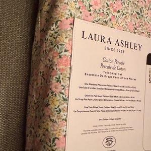 May include: Twin sheet set by Laura Ashley, featuring a floral pattern in pink, yellow, and green. The set includes a flat sheet (66 in x 96 in), a fitted sheet (39 in x 75 in), and a pillowcase (21 in x 32 in). Made of 100% cotton.
