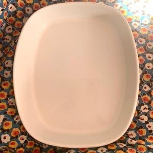May include: White ceramic baking dish with a rounded rectangular shape. The dish is empty and has a smooth, glossy finish.