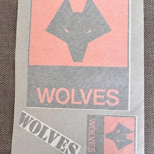 May include: A sheet with a gray wolf head logo on a salmon-colored background, with the word "WOLVES" in a bold font. Additional smaller logos and text are also present.