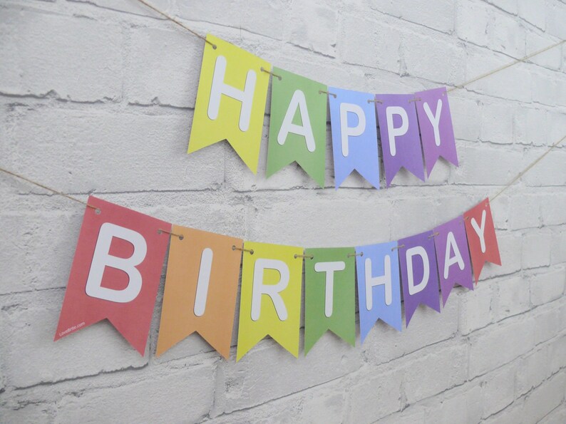 May include: A colorful banner with the words "HAPPY BIRTHDAY" in white letters. The pennants are in rainbow colors and strung on a natural twine, perfect for a birthday celebration.