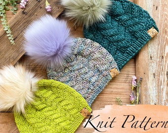 May include: Three knitted hats with faux fur pom poms in green, purple, and yellow. The hats are on a wooden surface with a sign that says "Knit Pattern".