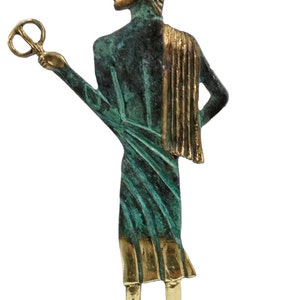 May include: A bronze statue of a Greek god, standing on a base with a Greek key design. The statue is green and gold, and the god is holding a key in his right hand.
