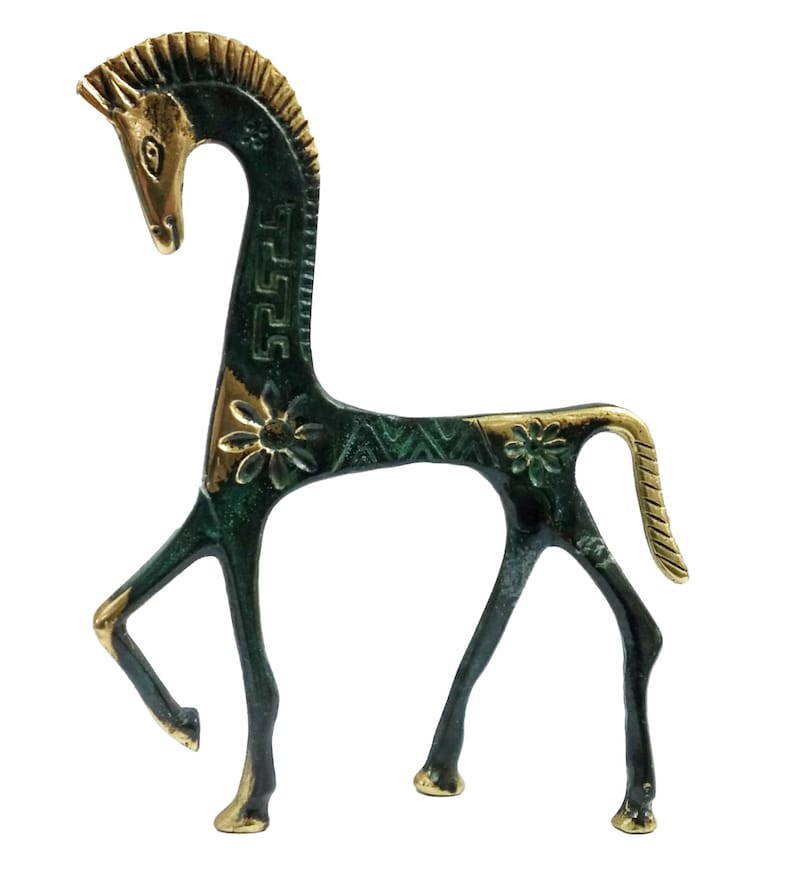 May include: A stylised metal horse figurine featuring a dark green patina finish with polished gold-tone accents on the mane, face, hooves, and tail. The body is decorated with engraved floral patterns and geometric Greek key motifs along the neck.
