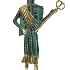 May include: A bronze statue of Hermes, the Greek god of messengers, commerce, and thieves. He is depicted wearing a winged helmet, a green tunic with a gold sash, and winged sandals. He holds a caduceus, a staff with two snakes entwined around it, in his right hand.