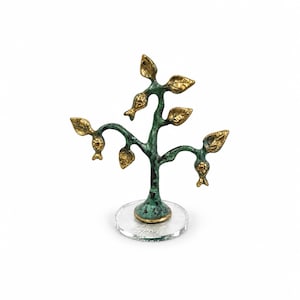 May include: A decorative tree sculpture featuring a textured, oxidized green trunk and branches with polished gold-toned leaves and small fruit-like accents. The sculpture is mounted on a clear, circular acrylic base for stability.