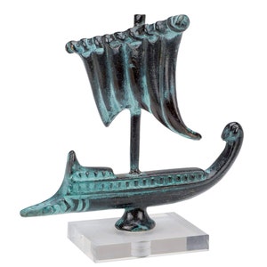 May include: A small, bronze statue of a Greek ship with a sail. The ship is painted in shades of green and black and is mounted on a clear acrylic base.