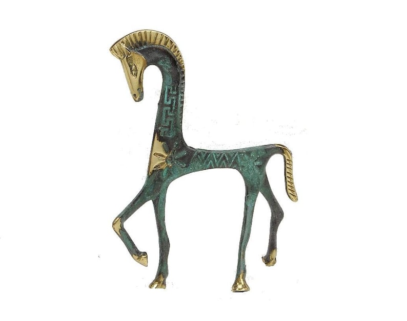 May include: A stylised horse figurine crafted from metal, featuring a combination of polished gold-tone brass and a weathered, oxidised green patina finish. The design includes geometric patterns along the neck and body with a raised tail.