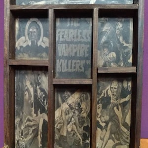 May include: A wooden shadow box with six compartments, each containing a vintage movie poster featuring the text "Fearless Vampire Killers". The box has ornate gold metal corners.