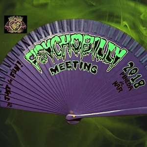 May include: Purple hand fan with a green and black graphic that says "Psychobilly Meeting 2018 Pineda de Mar" and the text "Just for Fun!"