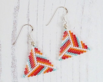 May include: A pair of silver triangle earrings with a geometric pattern of red, orange, white, and blue beads.