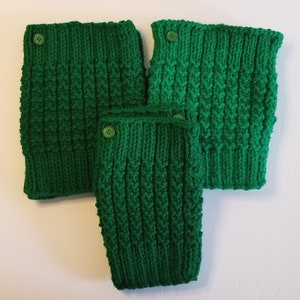 May include: Three knitted green leg warmers with a textured pattern and a button closure. The leg warmers are arranged in a layered composition, showcasing their varying sizes and textures. The vibrant green color adds a pop of color.