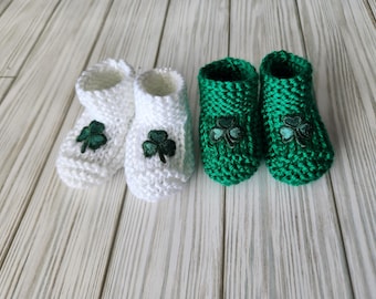 May include: Two pairs of baby booties, one white and one green, with shamrock embroidery.