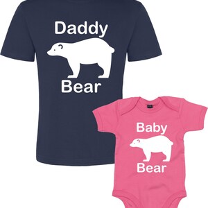 May include: A navy blue t-shirt with the text "Daddy Bear" and a white polar bear graphic. A pink baby onesie with the text "Baby Bear" and a white polar bear graphic.