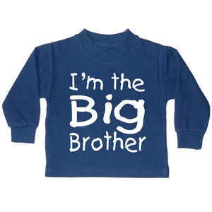 Może przedstawiać: Niebieska koszula z długim rękawem z napisem "I'm the Big Brother" w kolorze białym.