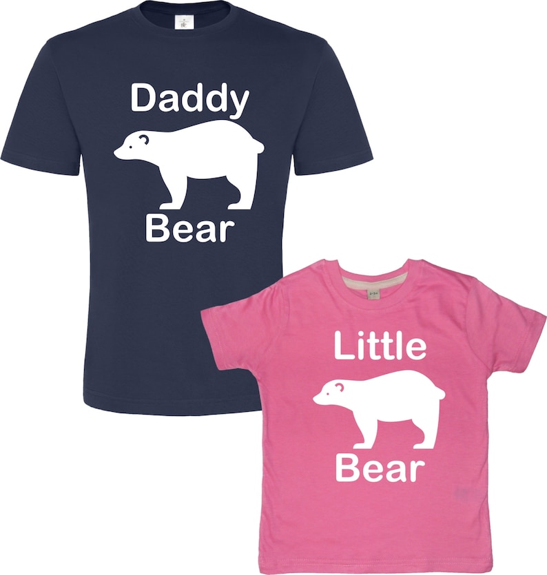 May include: A navy blue t-shirt with the text "Daddy Bear" and a white polar bear silhouette. A pink t-shirt with the text "Little Bear" and a white polar bear silhouette.