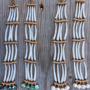 May include: Four pairs of long, white, beaded earrings with gold accents. The earrings have a layered design with white beads and gold spacers. The bottom of each earring is adorned with either a pearl or a piece of abalone shell.