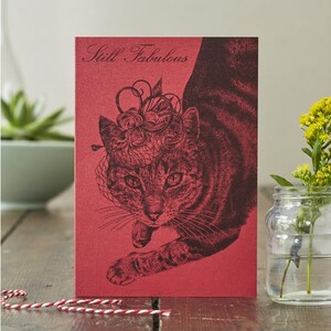 Stylische Katzenkarte: Katze im Hut Druck auf schimmernder, roter Karte mit 'Still Fabulous' Beschriftung. Muttertag oder jede Anlasskarte für Katzendamen!