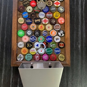 May include: A wooden wall mounted bottle opener with a metal bottle cap catcher. The opener has a variety of bottle caps attached to it.