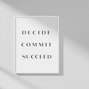 Könnte beinhalten: Ein weißer gerahmter Druck mit den Worten "DECIDE COMMIT SUCCEED" in schwarzem Text.