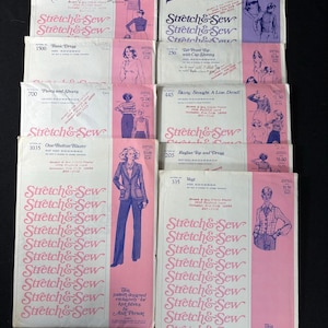 May include: A selection of vintage sewing patterns from "Stretch & Sew". The patterns showcase illustrations of clothing items such as dresses, blazers, and tops. The covers are pink and white, with the brand name repeated in a decorative style.