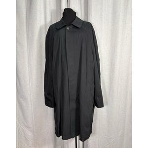 May include: A long, black coat with a button closure and a collar. The coat is displayed on a black mannequin. The coat appears to be made of a smooth, possibly water-resistant fabric. The coat is a classic style.