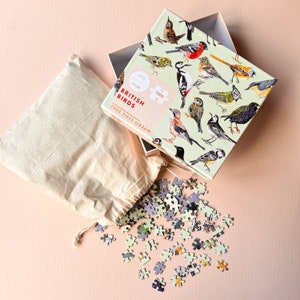 May include: A 1000 piece jigsaw puzzle of British birds in a white box with a drawstring bag. The box has a green background with illustrations of various birds. The text on the box reads "Little Pieces Jigsaw, British Birds, 1000 Piece Jigsaw".