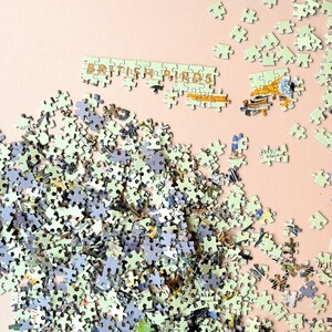 May include: A completed jigsaw puzzle with a light green background. The puzzle pieces are arranged to form the words "British Birds" in a gold font. The puzzle pieces are scattered around the edges of the image.