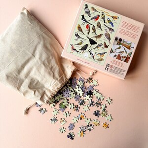 May include: A 1500 piece jigsaw puzzle of British birds in a brown paper bag. The puzzle box shows a colorful illustration of various birds with their names. The box is 44 x 30 cm.
