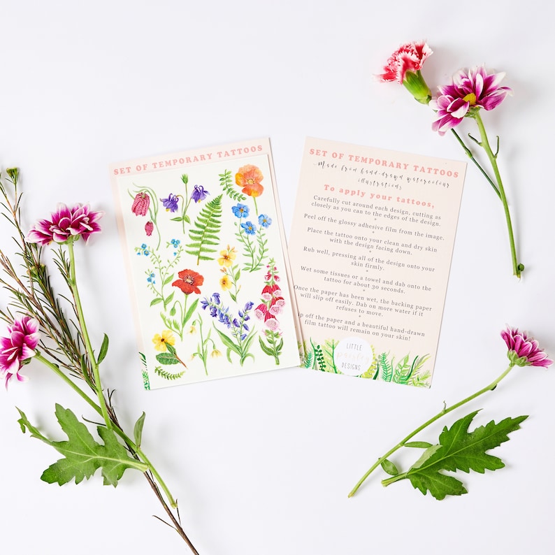 Puede incluir: Conjunto de tatuajes temporales con ilustraciones florales de colores. Los tatuajes est&aacute;n sobre un fondo blanco con instrucciones sobre c&oacute;mo aplicarlos. El texto dice "Set of Temporary Tattoos Made from hand-drawn illustrations. To apply your tattoos..."
