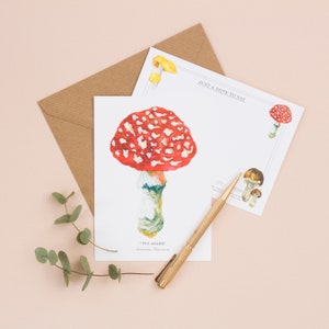 May include: A white card with a watercolor illustration of a red and white fly agaric mushroom. The card has the text "Fly Agaric Amanita Muscaria" and "Just a note to say..." printed on it.