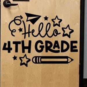 May include: A wooden door with a black door handle and a black decal that says "Hello 4th Grade." The decal includes a paper airplane, stars, and a pencil.