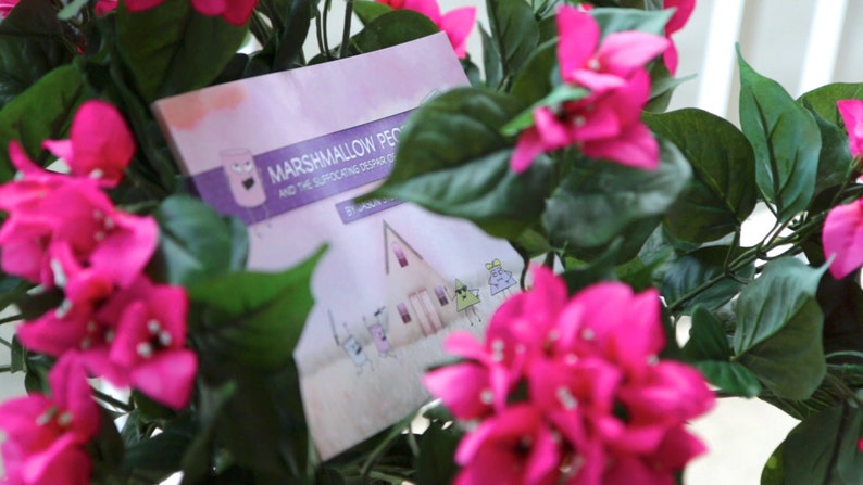 Puede incluir: Un folleto rosa y morado con el t&iacute;tulo "Marshmallow People and the Surrounding Denizens" sobre un fondo de flores rosas.