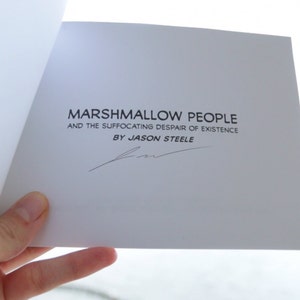 Puede incluir: Una cubierta de libro blanca con el t&iacute;tulo "Marshmallow People and the Suffocating Despair of Existence" de Jason Steele. El libro est&aacute; firmado por el autor.