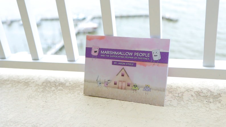 Puede incluir: Un libro titulado "Marshmallow People and the Suffocating Despair of Existence" de Jason Steele. La portada presenta un fondo morado y rosa con una casa y personajes de dibujos animados.