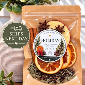 May include: A clear plastic pouch with a brown paper backing containing stovetop potpourri. The label reads OH SEW COZY CO HOLIDAY STOVETOP POTPOURRI COZY HOME just add water NATURAL INGREDIENTS. Visible ingredients include dried orange slices, cinnamon sticks, star anise, cloves, and rosemary.