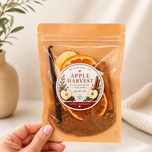May include: A kraft paper pouch containing stovetop potpourri with a label reading Oh Sew Cozy Co Apple Harvest Stovetop Potpourri Cozy Home just add water. The pouch holds dried orange slices, a cinnamon stick, and a vanilla bean.