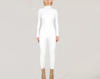 Op de afbeelding: Een witte, lange jumpsuit met een turtleneck. De jumpsuit is strak en heeft een stijlvol, modern ontwerp. Het model draagt gouden platformlaarzen.