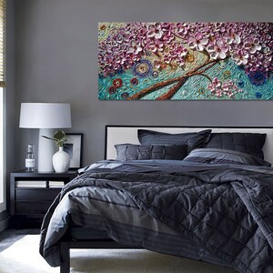 Op de afbeelding: Een groot canvas schilderij van een roze en witte bloeiende boom met een blauwe en groene achtergrond. Het schilderij heeft een textuur, 3D-effect.