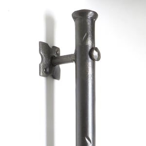 May include: A black metal door handle with a cylindrical design and two square mounting plates. The handle is textured and has a slightly distressed finish.