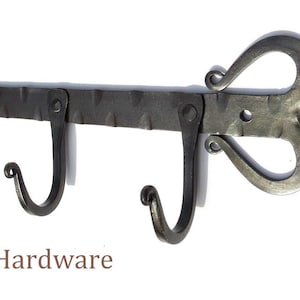 Könnte beinhalten: Ein schwarzer Wandhaken aus Metall mit vier Haken. Der Haken hat ein dekoratives herzförmiges Design am rechten Ende. Der Text "Tribes Iron Hardware" ist unter dem Haken sichtbar.