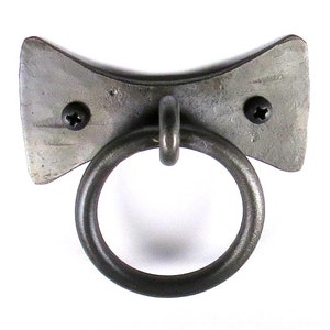 May include: A silver metal ring pull handle with a bow-shaped base. The handle is attached to a wall with two screws.