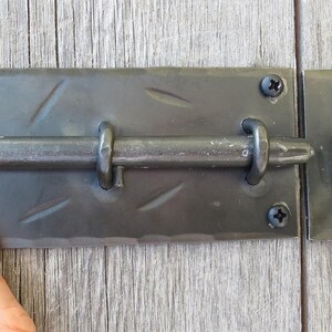 Puede incluir: Pestillo de puerta de metal negro con un patr&oacute;n de diamante en la placa y un gancho en el lado derecho.