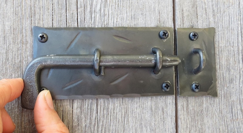 Puede incluir: Pestillo de puerta de metal negro con un patr&oacute;n de diamante en la placa y un gancho en el lado derecho.