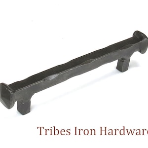 Może przedstawiać: Czarny metalowy uchwyt do szafki z młotkowanym wykończeniem. Uchwyt ma około 12,7 cm długości.