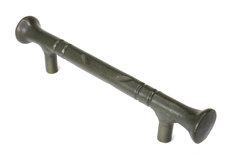 May include: A dark gray metal cabinet pull with a textured finish and a slightly curved design. The pull has a rounded end on each side.